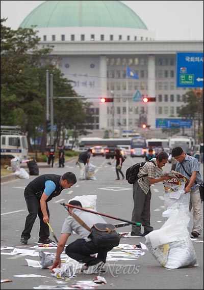 국회앞 도로에 어지럽게 버려진 유인물 등 쓰레기들을 민주노총 간부와 상근자들이 모두 치우고 있다.