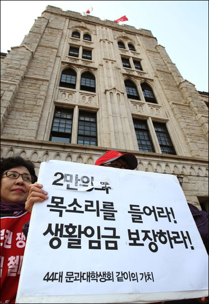  고려대학교 본관 앞에서 열린 '미화노동자 생활임금쟁취! 고대·연대·이대 파업투쟁 승리 결의대회’에 참가한 공공노조 서경지부 고려대분회 조합원이 손피켓을 들고 서 있다.