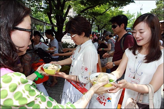 파업중인 MBC노조원들이 '82쿡' 회원이 건네는 전복과 인삼이 듬뿍 들어간 삼계탕을 받아들고 있다.