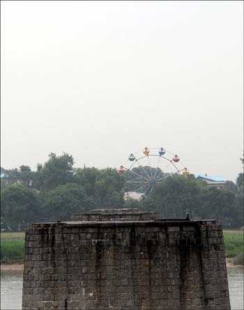 끊어진 압록강 철교. 다리 기둥 나머러 보이는 곳이 북한 신의주 땅이다. 어린이 놀이시설이 서 있지만 경제난으로 수년 째 운영되지 않고 있다.   