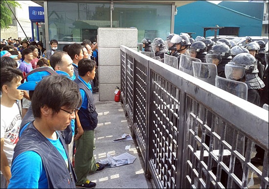 27일 경기 안산 에스제이엠 공장 앞에서 조합원들이 용역과 대치하고 있다. 용역은 헬멧, 방패, 진압봉 등으로 무장하고 있다. 