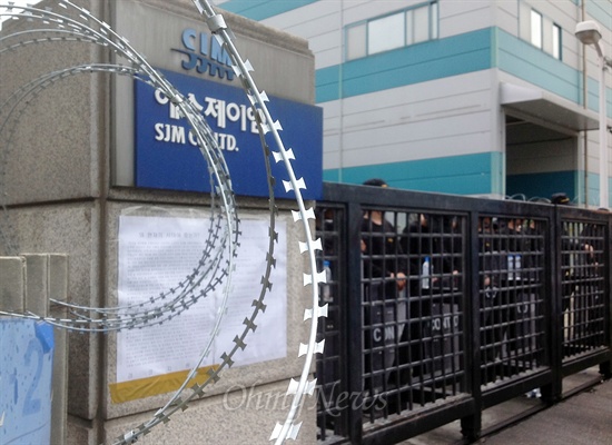 지난 7월 27일 직장폐쇄로 용역업체가 들어간 경기도 안산 반월공단의 자동차 부품업체 에스제이엠(SJM). 컨택터스라는 용역업체가 고용한 인력들이 공장 후문을 막고 서 있다.