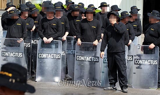 지난 2일 오후 직장폐쇄된 경기도 안산 SJM공장에서 용역업체 '컨택터스' 직원들이 철조망이 쳐진 정문안쪽에서 방패를 들고 서 있다.