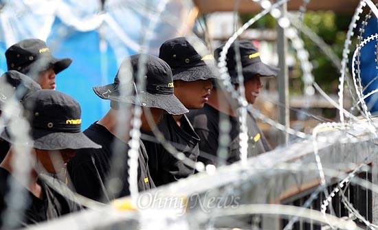 2일 오후 직장폐쇄된 경기도 안산 SJM공장에서 용역업체 '컨택터스' 직원들이 철조망이 겹겹이 쳐진 정문안쪽에서 방패를 들고 서 있다.