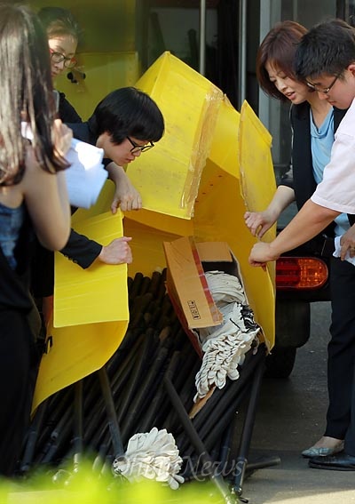 장하나 의원과 진선미 의원이 공장 앞 마당에 세워진 '컨택터스' 장비차량에서 곤봉을 확인하고 있다.