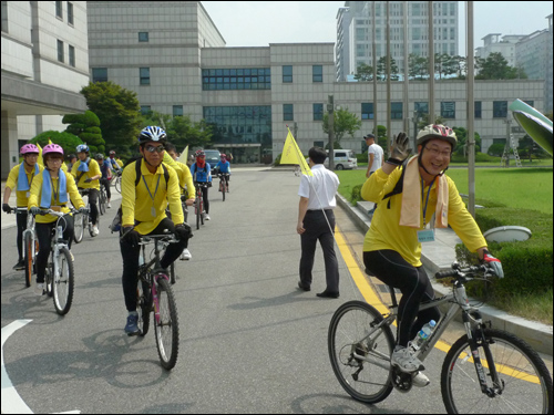 자전거 여행단에 자원봉사자로 참여한 이야기너머 정흥모 대표가 환한 미소로 "잘 다녀오겠다"고 말하며 출발하고 있다.