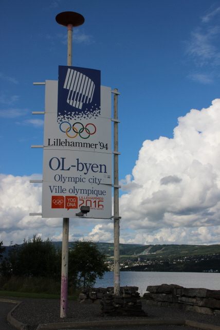 릴레함메르 동계올림픽 엠블렘 뒤로 릴레함메르시와 스키점프대가 보인다.