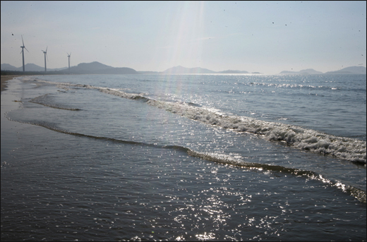 신안 비금도의 명사십리해변. 풍력발전기와 어우러진 해변에 한낮의 햇볓이 내리쬐면서 바닷물이 반짝반짝 빛을 내고 있다.