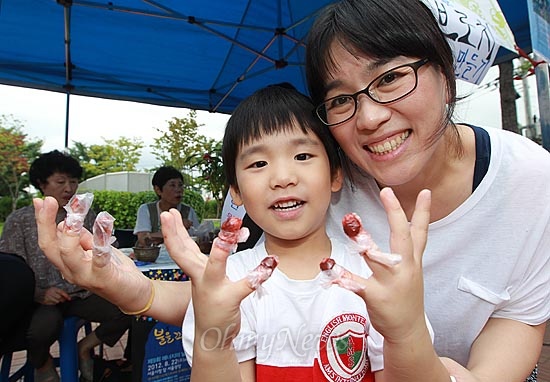  '제1회 성대골 에너지 축제-불을 끄고 별을 켜다'에 참가한 배시훈 어린이가 어머니와 함께 손톱에 봉숭아 물을 들인 손을 보여주며 환하게 웃고 있다.