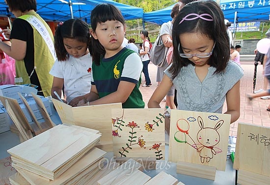 어린이들이 나무판에 직접 그림을 그려 냄비 받침을 만드는 체험을 하고 있다.
