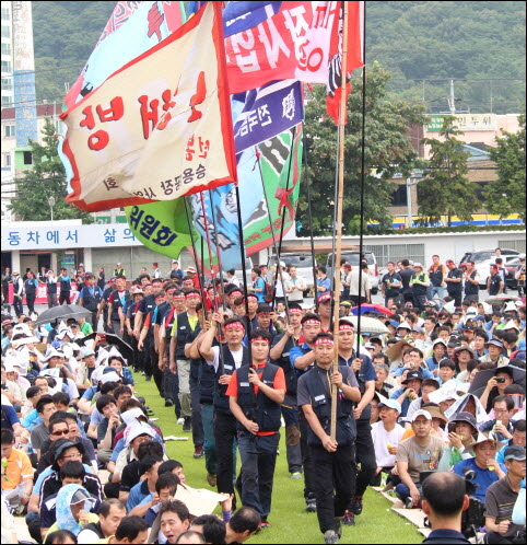 지난 5월 31일 현대자동차 울산공장 본관 앞 잔디마당에서 열린 '2012년 단체교섭 출정식'에서 현대차노조 조합원들이 깃발을 들고 입장하고 있다. 현대차노조는 당시 비정규직의 정규직화를 이루겠다고 약속했다 