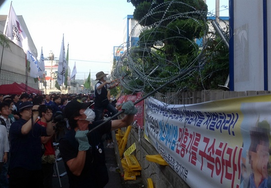 29일 경기도 안산에서 개최된 민주노총 총파업 집회에서 참가자들이 용역폭력 사태가 발생한 에스제이엠 공장에 설치된 철조망을 뜯어내고 있다.