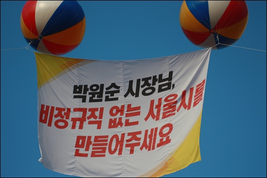 서울시청광장 에드벌룬에는 '박원순 시장님 비정규직 없는 서울시를 만들어주세요'라는 구호가 걸린 깃발이 펄럭인다.
