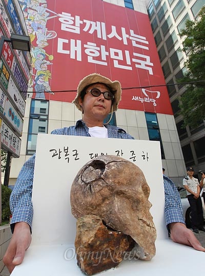  오종선 작가가 7일 오전 서울 여의도 새누리당 당사 앞에서 고 장준하 선생 의문사의 재조사를 촉구하며 고 장 선생 유골을 본떠 만든 조각 작품을 들고 전시회를 하고 있다.
