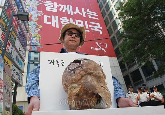  오종선 작가가 지난 7일 오전 서울 여의도 새누리당 당사 앞에서 고 장준하 선생 의문사의 재조사를 촉구하며 고 장 선생 유골을 본떠 만든 조각 작품을 들고 전시회를 하고 있다. 