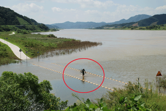 지난 5일 공주시 검상동에 있는 자전거도로가 침수되어 이용객이 자전거를 들고 건너고 있다.
