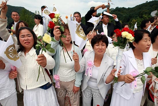 통일교 신도들이 장지로 향하는 운구행렬을 향해 꽃과 깃발을 흔들고 있다.