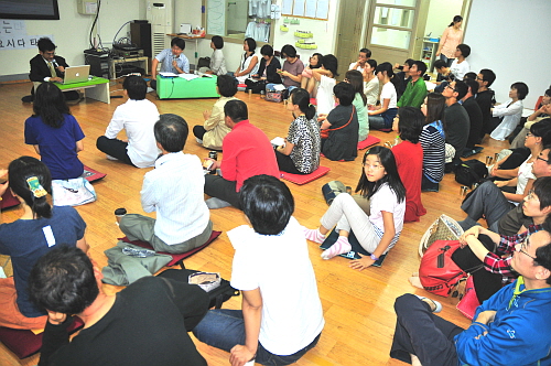 50명 이상의 참가자들이 한자리에 모여 요시다 타로의 강연을 경청하는 모습
