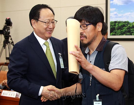  20일 국회 환경노동위원회에서 열린 쌍용자동차 정리해고 사태 청문회에서 증인으로 출석한 이유일 쌍용차 대표이사가 한상균 금속노조 쌍용차 전 지부장이 입장하자 다가가 악수를 하고 있다.