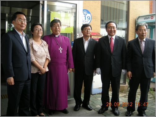 나우학교 현판 앞에서  김근상 주교, 김지선 교장. 김성환 구청장. 노회찬 의원. 등이 보인다.