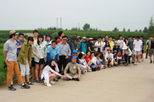  고산자 지역에 있는 신흥무관학교 옛터 답사를 마치고 기념 촬영. 뒤로 보이는 옥수수 밭이 신흥무관학교 터이다.이 날 너무 더워서 여중생이 손으로 햇빛을 가리고 있다.