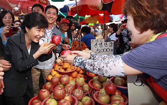 박근혜 새누리당 대선후보가 24일 오후 부산시 북구 구포시장에서 한 상인이 건네주는 사과를 들어보이며 추석물가에 대해 이야기를 나누고 있다.  