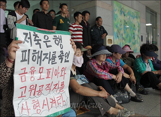 26일 오전 금융감독원이 주관하는 캠퍼스 금융토크 출입을 저지당한 부산저축은행 피해자들이 1층 출입구에 앉아서 연좌시위를 벌이고 있다. 