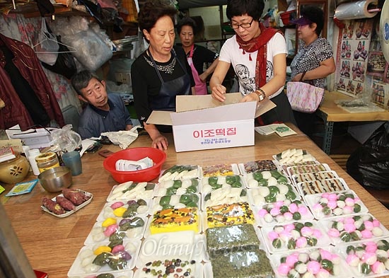  25일 오전 서울 관악구 봉천시장에서 <이조떡집>을 운영하며 나눔푸드를 실천하고 있는 조현옥 사장이 오는 추석을 위해 이웃에게 전달해 달라며 방금 만든 송편을 여용옥 라온제나(관악주민연대 여성모임) 회장에게 건네주고 있다.
