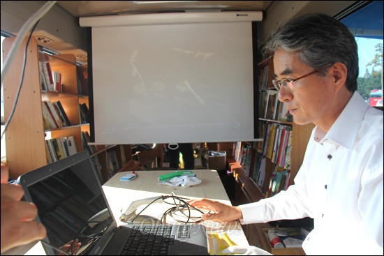 경남교육포럼은 소외지역을 찾아가는 '숲속도서관'을 운영한다. 사진은 박종훈 전 경남도교육의원이 버스 안에 슬치된 스크린에 영화를 상영해 보이는 모습.
