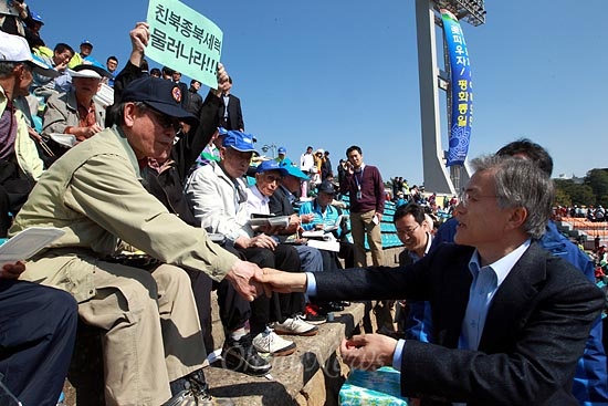 문재인 후보가 관중석을 돌며 참석자에게 인사를 하는 가운데, 한 참석자가 '친북종북세력 물러나라"가 적힌 손피켓을 들고 있다.