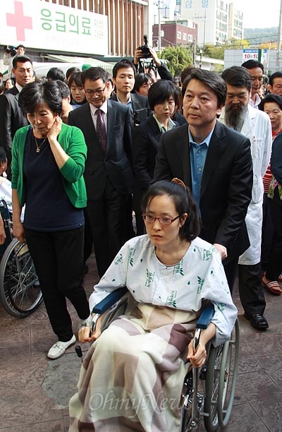  안철수 무소속 대선후보가 한혜경씨를 만나 고충을 듣고 위로한 뒤 휠체어를 직접 밀어주고 있다.