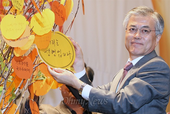  문재인 민주통합당 대선후보가 18일 오후 서울 양재동 aT센터에서 열린 '위기의 먹거리, 희망을 말하다' 토론회에 참석해 희망사과나무에 '먹거리는 생명입니다'라는 글귀를 매달고 있다.