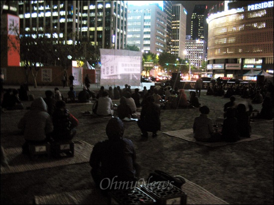 23일 오후 7시 서울 시청광장에서 시민들이 영화 <유신의 추억>을 보고 있다.