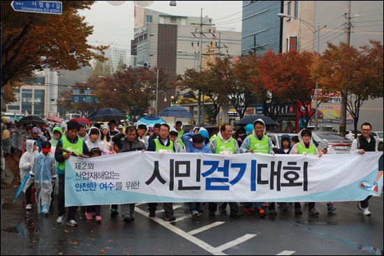  '제2회 산업재해 없는 안전한 시민걷기대회' 펼침막을 들고 참가자들이 학동 여수소방서 앞을 지나고 있다. 