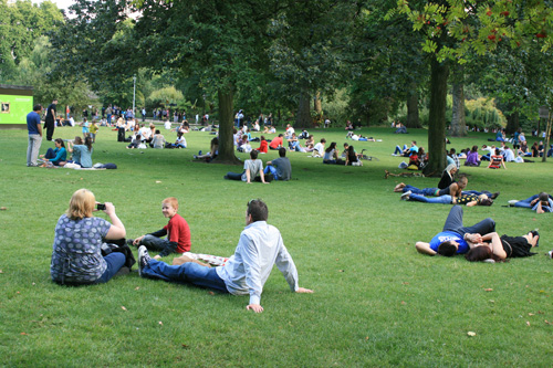 가족과 연인들이 푸른 잔디밭에서 휴식을 취하고 있다.
