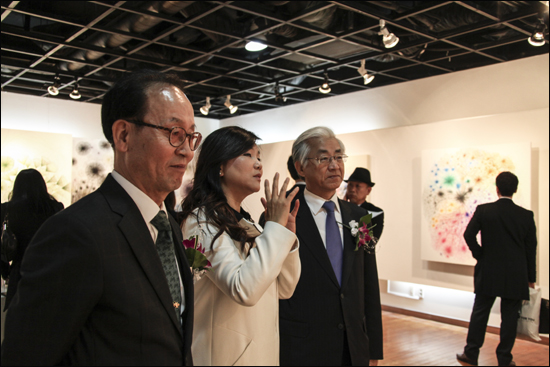박지숙 교수와 작품전을 함께 관람하고 있는 이봉기 코모스유통 대표(왼쪽, 뿔테 안경 쓴 이)
