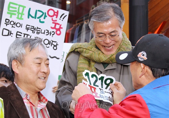 문재인 민주통합당 대선후보가 14일 오후 부산 서면로터리에서 열린 투표시간 연장 캠페인에 참석해 한 시민이 건넨 '1219 투표참여' 캠페인 스티커를 옷에 붙이고 있다.