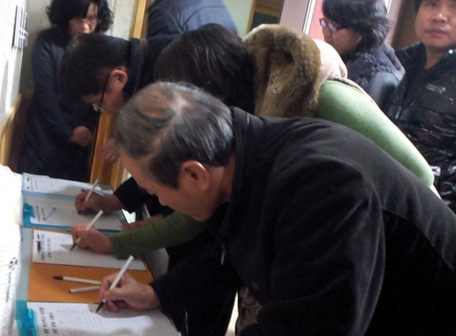 지난 18일 오후 6시쯤 서울 천왕초 학부모들이 천왕중에 대한 혁신학교 지정을 요구하는 청원서에 서명하고 있다. 