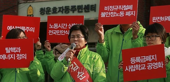 청소노동자 김순자씨가 지난달 21일 오전 서울 종로구 청운동사무소에서 대선출마선언 기자회견을 열고 있는 가운데 대선공약이 써있는 손피켓을 지지자들이 들고 있다.