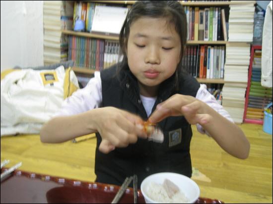 흑돼지를 엄마가 담근 김치에 말아 먹는 딸 아이.