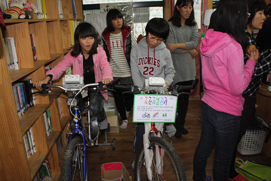 도서관에 온 아이들이 자전거발전기 페달을 밟아 전기를 생산하고 있다.
