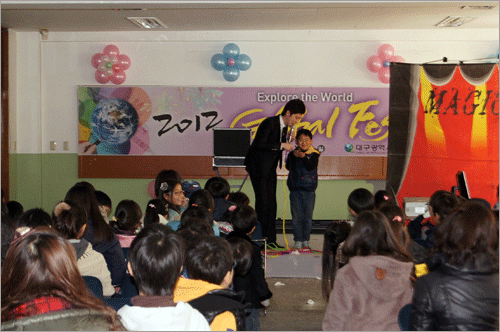 한 아동 참가자에게 마술시연을 해보이고 있는 광경 참가 아동들의 흥미를 높이기 위해 마술배우기를 하고 있는 광경