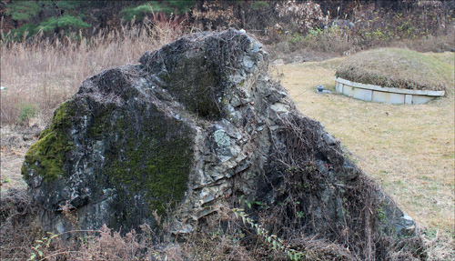 상계1리 칠성고개로 넘어가는 길목에서 본 고인돌 중 하나. 청동기 시대의 무덤 뒤로 현대의 묘소가 보인다. 