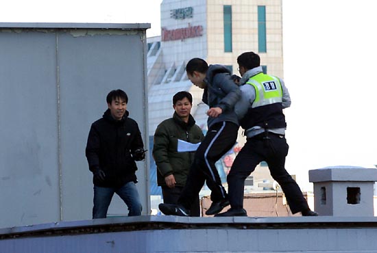  26일 오후 2시23분께 서울시 공평동 안철수 캠프 옆 빌딩 옥상에서 한 남자가 투신소동을 벌이며 경찰과 대치하고 있는 가운데 뒤쪽에서 다가선 경찰관이 이 남자를 제압하고 있다.