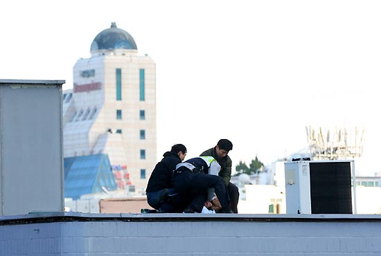  26일 오후 2시23분께 서울시 공평동 안철수 캠프 옆 빌딩 옥상에서 투신소동을 벌이던 남자를 경찰관들이 제압하고 있다.