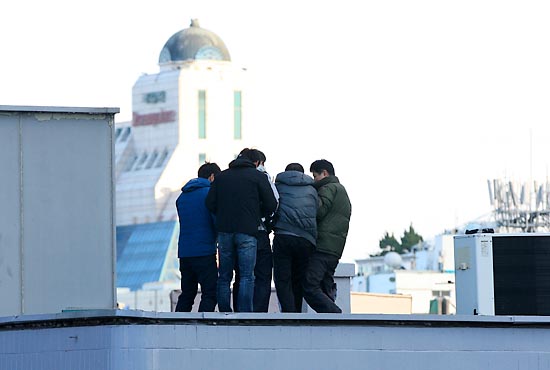  26일 오후 서울시 공평동 안철수 캠프 옆 빌딩 옥상에서 투신소동을 벌이던 남자를 경찰관들이 제압한후 연행하고 있다.