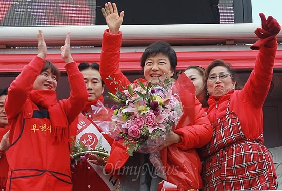 박근혜 새누리당 대선후보가 11월 30일 오후 부산 진구 부전시장을 찾아 상인들로부터 꽃다발을 건네받고 유권자들에게 지지를 호소하며 손을 흔들어보이고 있다.