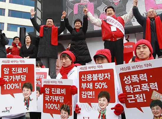 지난 2012년 12월 박근혜 당시 새누리당 대선후보가 강원도 강릉 택시부광장에서 유세하는 모습. 선거운동원이 '암 진료비 국가부담 100!'라고 쓴 피켓을 들고 있다.