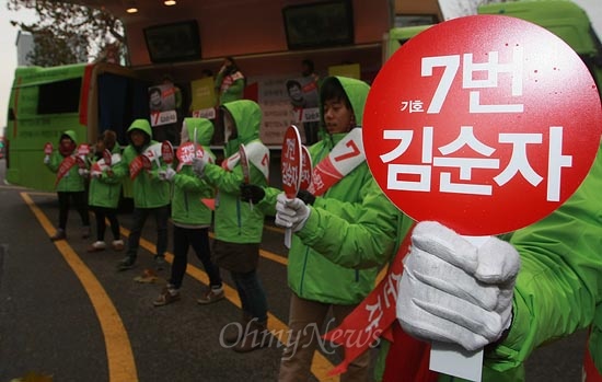 청소노동자 김순자 무소속 대선후보가 3일 오후 서울 영등포구 타임스퀘어 정문 삼거리에서 유세를 열고 있는 가운데 선거사무원들이 '기호7번 김순자'라고 쓰여진 손피켓을 들고 응원하고 있다.