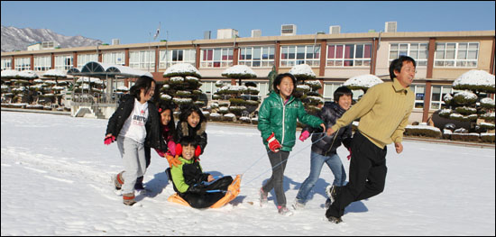 6일 경남 함양군 지곡면 지곡초등학교 운동장에서 선생님과 어린이들이 마대 포대를 이용해 썰매를 타며 즐거운 시간을 보내고 있다.
